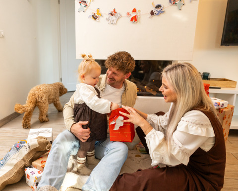 Family opening gifts together in Wellness Lodge XL at Hof van Salland, Netherlands, with their dog nearby.