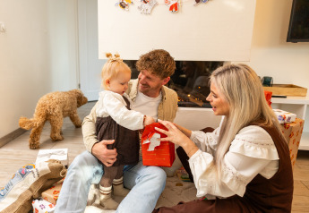 Famille ouvrant des cadeaux à la Wellness Lodge XL à Hof van Salland, Pays-Bas, avec leur chien.