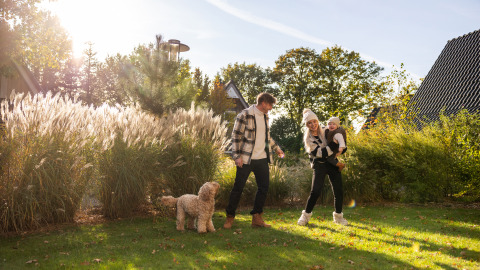 Familia con niño y perro disfruta del sol frente a la Wellness Lodge XL en Hof van Salland, Países Bajos.