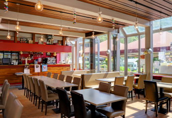 Bright, modern café area at a glamping resort featuring large windows, ample seating, and a bar.