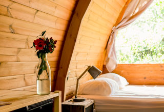Bright wooden interior of Duo Panorama pod at RØSTIG Dorst with a flower vase and view outside.