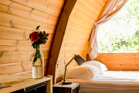 Intérieur en bois clair du Duo Panorama pød à RØSTIG Dorst avec un vase de fleurs et vue sur la nature.