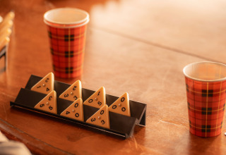 Mesa con vasos de papel a cuadros y piezas de juego triangulares en un alojamiento de glamping iluminado.