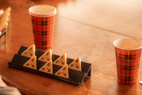 Tafel met geruite bekers en driehoekige spelfiches in een warme, gezellige glampingomgeving.