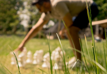 Wazig beeld van een persoon die buitenshuis reuzenschaak speelt op het gras bij een glampingverblijf.