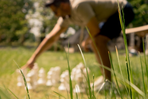 Unscharfes Foto einer Person, die auf einer Wiese bei einem Glamping-Aufenthalt Riesenschach spielt.