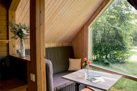 Intérieur cosy du tiny house Luxe & Lazy Lodge à RØSTIG Dorst, Pays-Bas, avec une grande vue sur la nature.