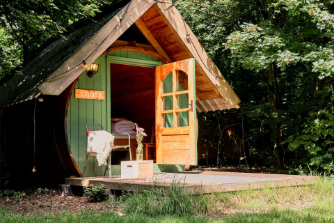 Gemütliche Holzhütte SOLO TØN im Wald bei RØSTIG Dorst, Niederlande, mit offener Tür und Terrasse.
