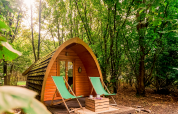 Duo pød at RØSTIG Dorst in the Netherlands, a wooden pod in the woods with two green deck chairs.
