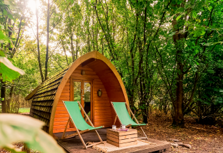 Pod de madera Duo pød en RØSTIG Dorst, Países Bajos, rodeado de bosque y dos tumbonas verdes.