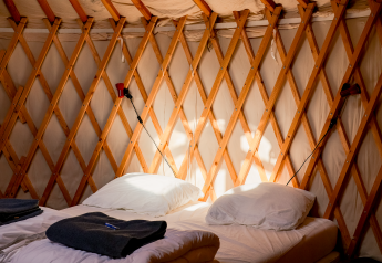 Interior acogedor de yurta con camas gemelas y entramado de madera en Yurt at RØSTIG Dorst, Países Bajos.