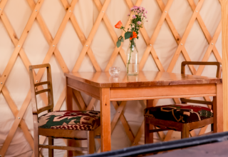 Houten tafel met twee stoelen en bloemenvaas in een yurt bij Yurt at RØSTIG Dorst, Nederland.
