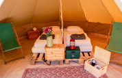 Interior of a teepee tent at RØSTIG Dorst in the Netherlands with twin beds, chairs, and rustic decor.