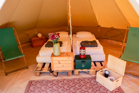 Interior of a teepee tent at RØSTIG Dorst in the Netherlands with twin beds, chairs, and rustic decor.