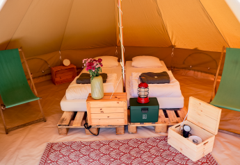 Interior of a teepee tent at RØSTIG Dorst in the Netherlands with twin beds, chairs, and rustic decor.