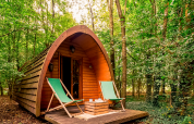 Duo Pod Large bij RØSTIG Dorst, Nederland, houten pod in het bos met twee groene stoelen buiten.