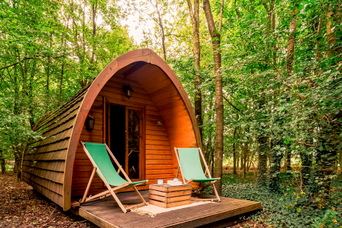 Duo Pod Large cabin at RØSTIG Dorst, Netherlands, nestled in the forest with two green outdoor chairs.