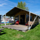 Tente safari Heeg à la Marina Heeg aux Pays-Bas, terrasse en bois, pelouse et bateaux proches.