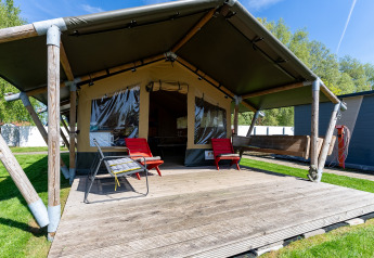 Tente safari Heeg à Marina Heeg aux Pays-Bas, terrasse en bois et chaises rouges extérieures.
