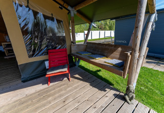 Außenbereich des Safari-Zelts Heeg in Marina Heeg, Niederlande, mit Holzbank und rotem Stuhl.