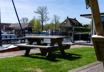 Blick vom Safari-Zelt Heeg an der Marina Heeg, Niederlande, mit Picknicktisch, Booten und Häusern.