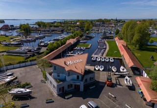 Vista aérea de la Safari tent Heeg en Marina Heeg, Países Bajos, con barcos y áreas verdes junto al agua.