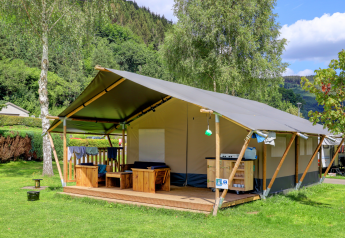 Eco Lodge MOBIWOOD en Camping Floreal La Roche-en-Ardenne, Bélgica, rodeada de árboles y naturaleza verde.