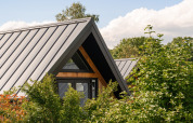 Casa pequeña Wellness Lodge en Holiday Park De IJsvogel, Países Bajos, con moderno techo y vegetación.