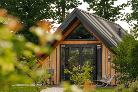 Tiny house Wellness Lodge con facciata in legno e grandi finestre al Holiday Park De IJsvogel, Paesi Bassi.