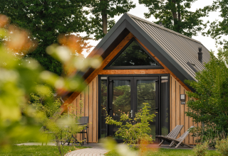 Tiny house Wellness Lodge met houten gevel en grote ramen bij Holiday Park De IJsvogel, Nederland.
