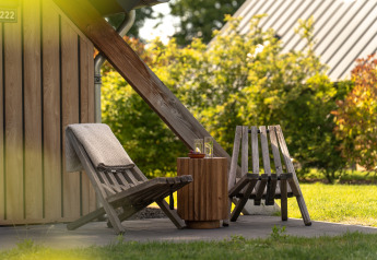 Area relax esterna alla Wellness Lodge, Holiday Park De IJsvogel, Paesi Bassi, con sedie e tavolino in legno.