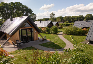 Tiny house Wellness Lodge en Holiday Park De IJsvogel, Países Bajos, rodeada de jardines y senderos.