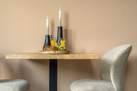 Mesa acogedora en Wellness Lodge, De IJsvogel, Países Bajos, con desayuno, velas y dos sillas.