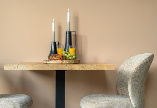 Tavolo accogliente al Wellness Lodge, De IJsvogel, Paesi Bassi, con colazione, candele e sedie.