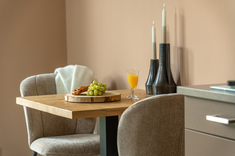 Small dining table with grapes, juice, and croissant in a cozy corner at Wellness Lodge, Holiday Park De IJsvogel.