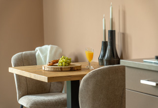 Pequeña mesa de comedor con uvas, jugo y croissant en la acogedora Wellness Lodge de Holiday Park De IJsvogel.