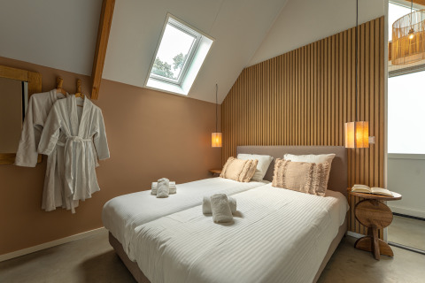 Camera moderna nella Wellness Lodge al Holiday Park De IJsvogel nei Paesi Bassi, con letto e accappatoi.