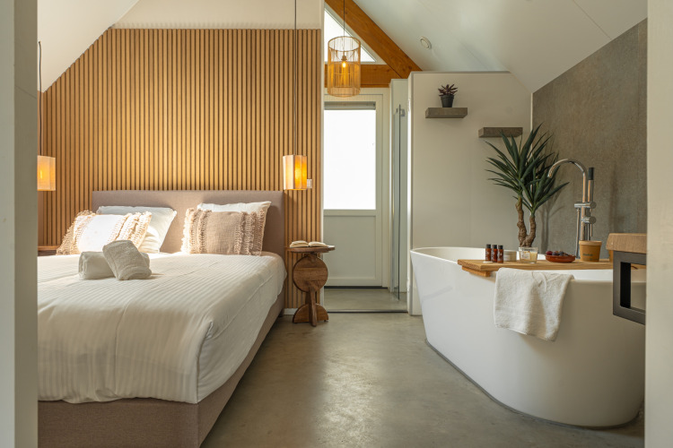 Dormitorio moderno y luminoso con bañera independiente en Wellness Lodge del Holiday Park De IJsvogel, Países Bajos.