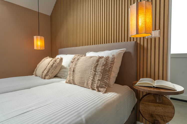Dormitorio moderno en Wellness Lodge de Holiday Park De IJsvogel, Países Bajos, con luz cálida y detalles de madera.