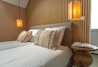 Dormitorio moderno en Wellness Lodge de Holiday Park De IJsvogel, Países Bajos, con luz cálida y detalles de madera.