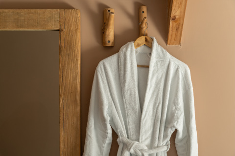 Accappatoio bianco su un gancio di legno nella Wellness Lodge di Holiday Park De IJsvogel, Paesi Bassi.
