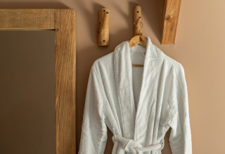 A white bathrobe on a wooden hook at the Wellness Lodge in Holiday Park De IJsvogel, Netherlands.