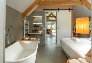 Modern wellness lodge at Holiday Park De IJsvogel in the Netherlands with bathtub and cozy bedroom area.