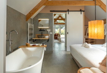 Moderne wellness lodge op Holiday Park De IJsvogel in Nederland met vrijstaand bad en gezellige slaapkamer.