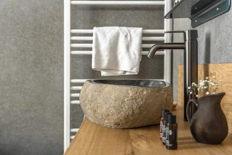 Steinwaschbecken und schwarze Armatur im Wellness Lodge Tiny House, Holiday Park De IJsvogel, Niederlande.