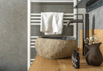 Stone sink and modern black faucet in the Wellness Lodge tiny house at Holiday Park De IJsvogel, Netherlands.