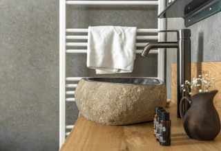 Steinwaschbecken und schwarze Armatur im Wellness Lodge Tiny House, Holiday Park De IJsvogel, Niederlande.