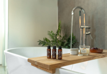 Escena de baño relajante en la Wellness Lodge con productos de spa y vela en Holiday Park De IJsvogel.