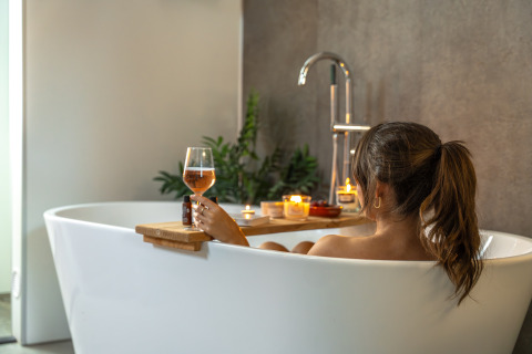 Donna si rilassa nella vasca da bagno con vino e candele al Wellness Lodge, Holiday Park De IJsvogel, Paesi Bassi.
