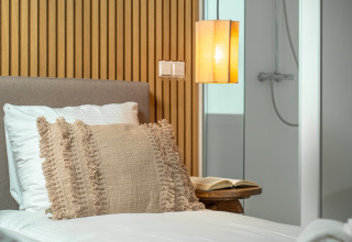 Dormitorio moderno en Wellness Lodge de Holiday Park De IJsvogel, Países Bajos, con luz acogedora y baño.